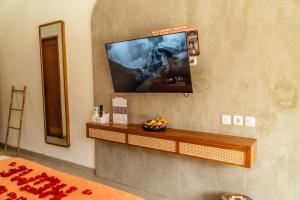 a room with a flat screen tv on a wall at Roomates Hostel Canggu by Ini Vie Hospitality in Canggu