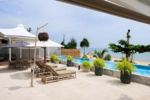 un patio con sillas y sombrillas junto a una piscina en Luxury Penthouse - Khanom en Ban Plau