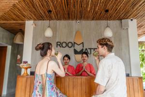 a man and woman eating food in front of a mirror at Roomates Hostel Canggu by Ini Vie Hospitality in Canggu
