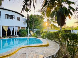 a villa with a swimming pool in front of a house at Casa Hera Diani in Diani Beach