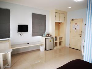 a room with a kitchen with a refrigerator and a tv at Baanchomchan in Hua Hin