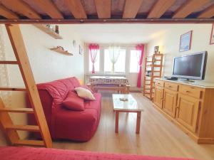 uma sala de estar com um sofá vermelho e uma televisão em La Mongie, Studio pieds des pistes, parking intérieur privé em La Mongie