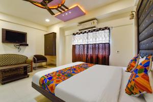 um quarto com uma cama, um sofá e uma televisão em FabHotel Crystal Inn II em Ahmedabad