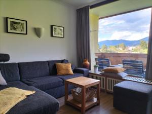 a living room with a blue couch and a large window at Apartment Almblick in Kaprun