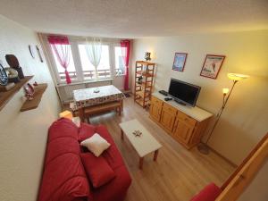 salon z czerwoną kanapą i telewizorem w obiekcie La Mongie, Studio pieds des pistes, parking intérieur privé w mieście La Mongie