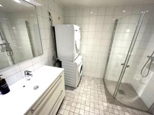 a bathroom with a refrigerator and a sink and a shower at Scandpoint Apartment Lillestrom -Cosy 3 rooms flat with Parking, EV Charger 18 min from Airport in Lillestrøm +8 photos