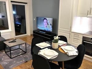 - un salon avec une table, des chaises et une télévision dans l'établissement Scandpoint Apartment Lillestrom -Cosy 3 rooms flat with free Parking, EV Charger 18 min from Airport, à Lillestrøm