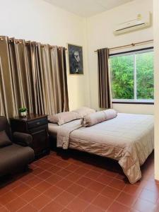 a bedroom with two beds and a chair and a window at The Rain tree, Pool villa Pattaya in Pattaya Central