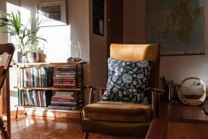 a chair with a pillow and a book shelf with books at Birdsong in Adventure Bay