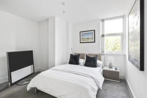 a white bedroom with a large bed and a window at Luxurious 2 Bedroom Apartment with Free Parking in Chelmsford
