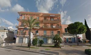 a tall orange building with a palm tree in front of it at Quilungomare in Porto Cesareo