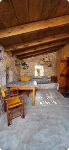 a wooden table and chairs in a room with a stone wall at La Casa Di Nonna in Koríthion
