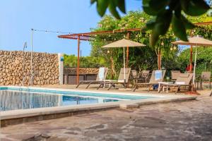 a pool with chairs and umbrellas next to a wall at Menorca Agroturismo Llimpet in Alaior