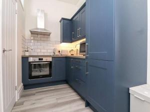 a kitchen with blue cabinets and a stove at The Hideaway - Perfect couples retreat with Free parking on driveway in Lytham St Annes