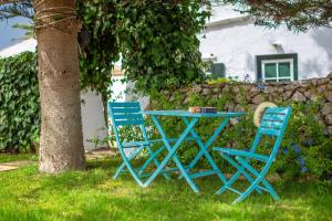 two blue chairs and a table next to a tree at Menorca Agroturismo Llimpet in Alaior