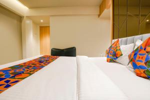 una camera da letto con un grande letto bianco con cuscini colorati di FabHotel Springs Lodging a Mire