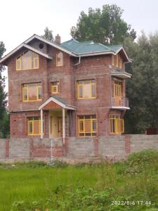 an old brick house with yellow windows in a field at Chand Tara paying Guest house in Srinagar