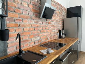 a kitchen with a brick wall and a sink at Apartamenty Brenna Klimorówka in Brenna