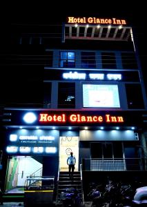 Hotel Glance Inn في Gulzārbāgh: شخص يقف خارج فندق مراقص بالليل