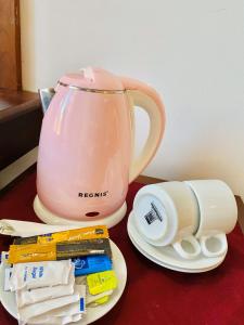 uma chaleira de chá rosa e um prato com pacotes de pasta de dentes em Ceylan Lodge em Anuradhapura
