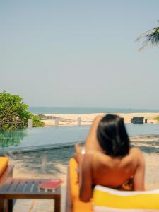 a woman sitting in a chair at the beach at The Postcard on the Arabian Sea in Udupi