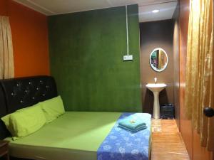 ein Schlafzimmer mit einem Bett mit einer grünen Wand in der Unterkunft Pondok Sri Salang in Kampong Telok Salang