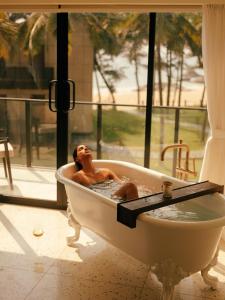 a woman laying in a bath tub in a window at The Postcard on the Arabian Sea in Udupi