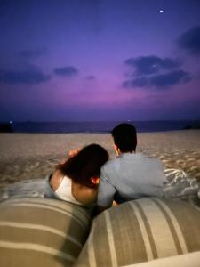 - un couple assis sur la plage avec vue sur l'océan dans l'établissement The Postcard on the Arabian Sea, à Udupi