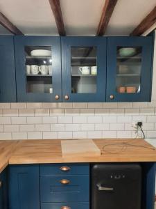 uma cozinha com armários azuis e um balcão de madeira em 18th-Century three-bedroom Mill Worker's Cottage em Cromford