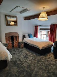 1 dormitorio con 2 camas y chimenea en 18th-Century three-bedroom Mill Worker's Cottage, en Cromford