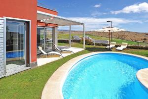 una piscina en un patio con sillas y sombrilla en Salobre Vista Golf 1 en Maspalomas