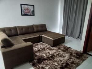 a living room with a brown couch and a rug at Maison Guriri in São Mateus