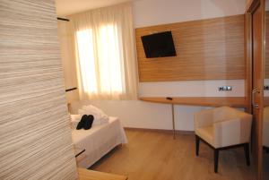 トッサ・デ・マールにあるHotel Victoriaのベッド、デスク、椅子が備わる客室です。