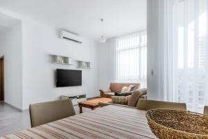 a living room with a table and chairs and a television at Bright Apartment minutes from the Sea in Il-Gżira