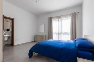 um quarto com uma cama azul e uma janela em Bright Apartment minutes from the Sea em Il-Gżira