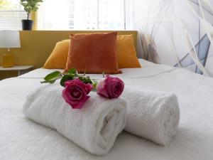 a bed with towels and two roses on it at Open Mind Property - Luxury Apartment in the City in Portsmouth