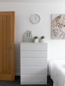 a white dresser in a bedroom with a clock on the wall at Open Mind Property - Luxury Apartment in the City in Portsmouth