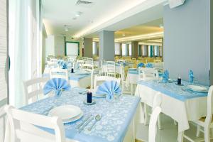 uma sala de jantar com mesas e cadeiras azuis e brancas em Hotel Bolivar em Lido di Jesolo