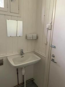 uma casa de banho branca com um lavatório e um espelho em Stugan em Lemland