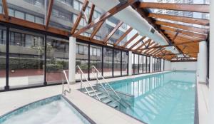 uma piscina interior num edifício com janelas em ReadySet Apartments on Kavanagh em Melbourne