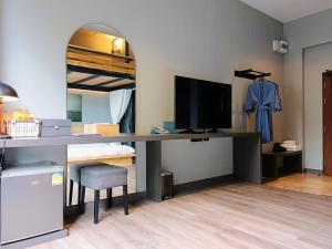 een slaapkamer met een bureau, een televisie en een bed bij 233Poshtel in Lampang