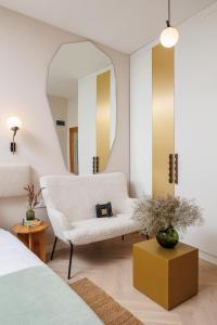 a bedroom with a white chair and a mirror at Aries' Collection Luxury Suites in Braşov
