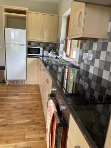 a kitchen with a white refrigerator and wooden floors at Creevagh Cottage in Castlebar