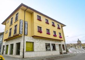 a yellow building with red flower boxes on it at Hospedería Puerta de la Catedral in Ciudad-Rodrigo +12 photos