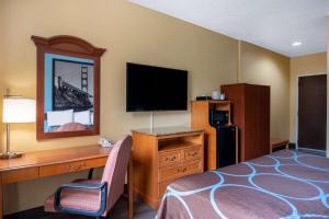 a hotel room with a bed and a desk with a television at Super 8 by Wyndham Salisbury in Salisbury