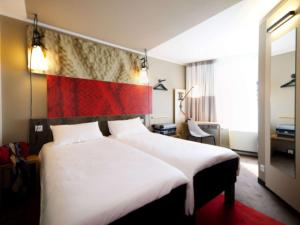 una habitación de hotel con una gran cama blanca con una bandera en la pared en ibis Köln Centrum, en Colonia