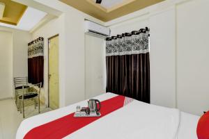 a bedroom with a white bed with a red blanket at Flagship Ap Royal Rooms in Nagpur