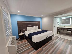 a bedroom with a bed and a blue wall at Travelodge Inn & Suites by Wyndham Fullerton in Fullerton