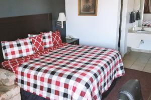 a bedroom with a bed with a red and white checkered blanket at Sky-Palace Inn & Suites Hutchinson in Hutchinson