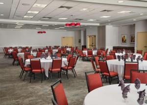 a banquet hall with white tables and red chairs at Hilton Garden Inn Ann Arbor in Ann Arbor